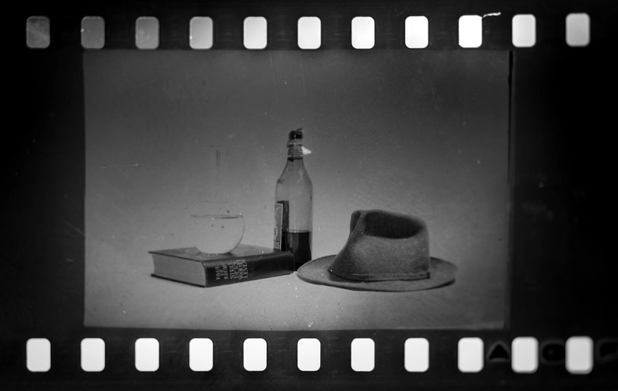 A black and white still life seen inside the sprocket holes of a film frame